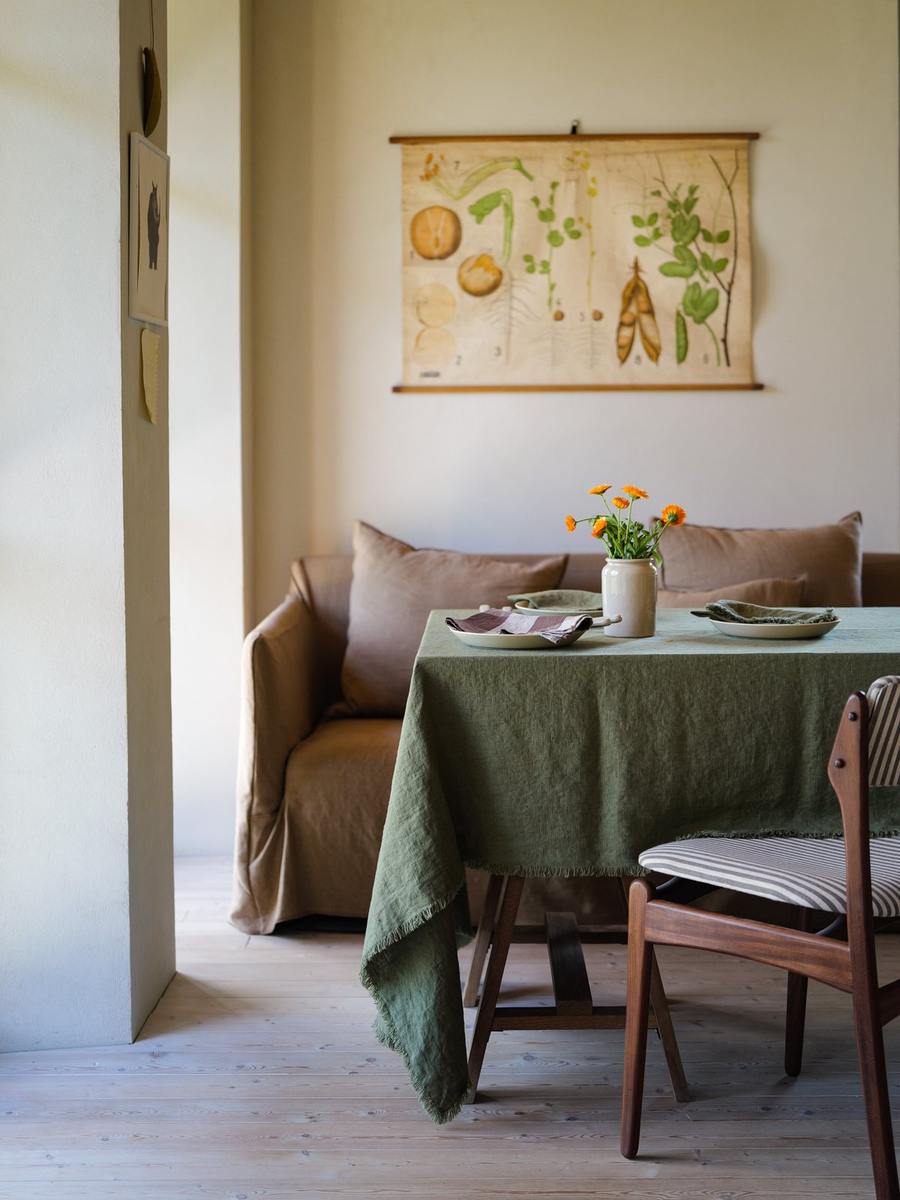 Olive Green Terra Fringe linen tablecloth with cream plates and orange flowers