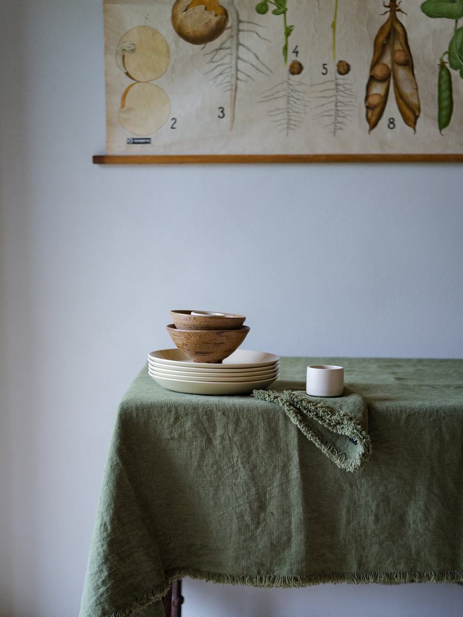 Cream plates and wooden bowls on olive green linen