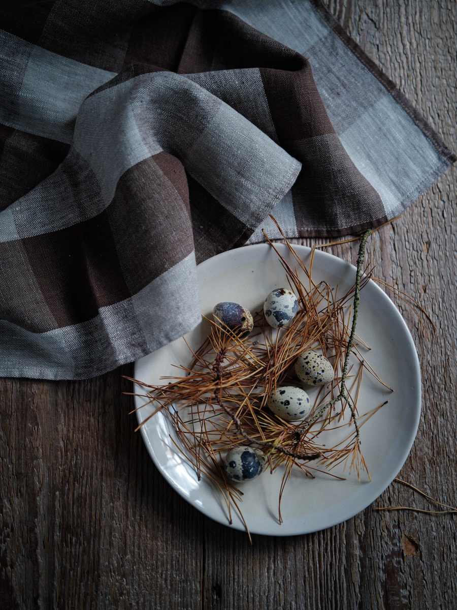 Chocolate checked linen beside a cream plate with quail eggs