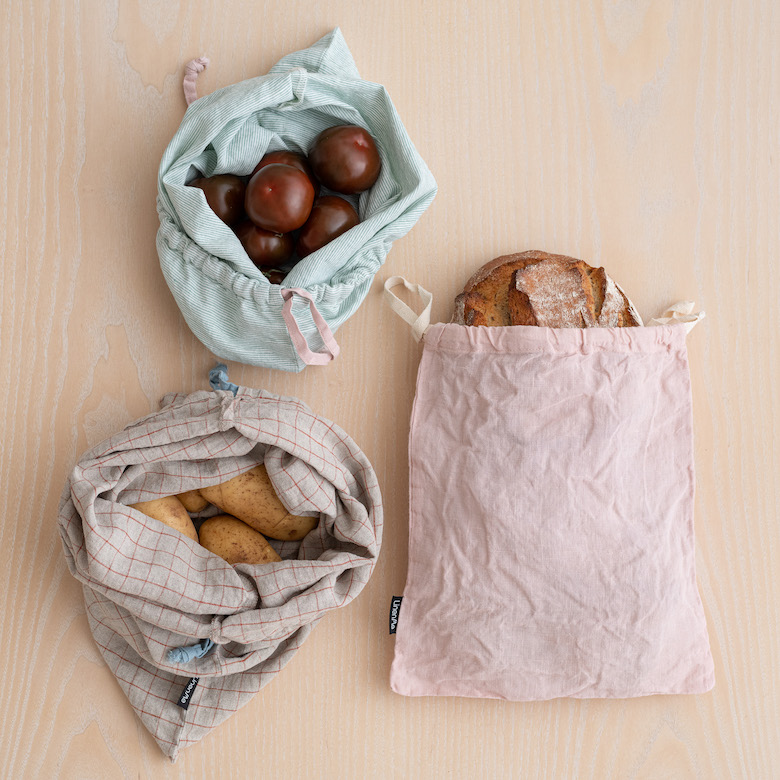 sustainable linen bags filled with bread, fruit and food