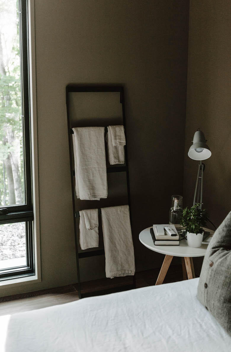 Linen towels and textiles folded on a wooden ladder in the Birch Le bedroom