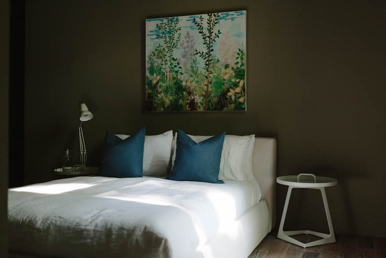 Dark modern bedroom with white linen bedding and blue linen cushions