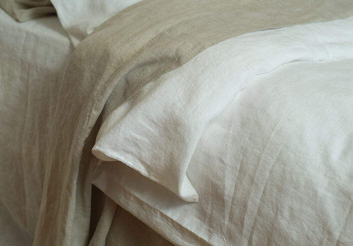 Helle Stonewashed-Leinenlaken auf einem Bett