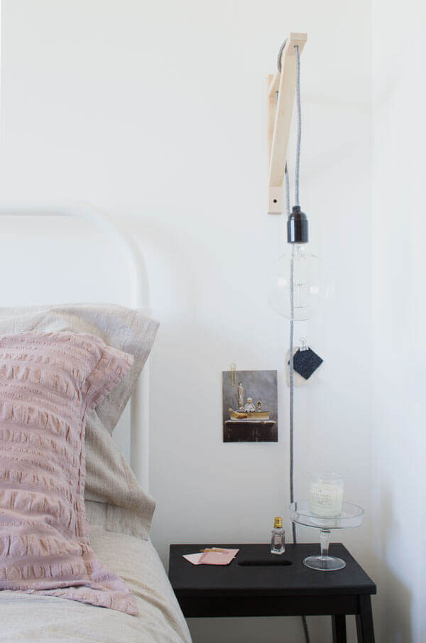 Dark bedside table contrasting with a light bed