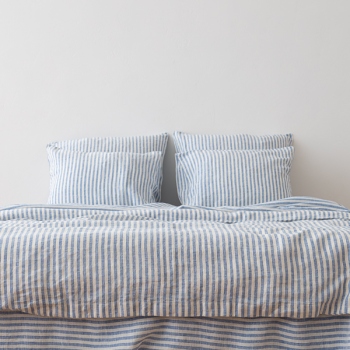 Blue Ticking Stripe linen bedding on a bed, front view