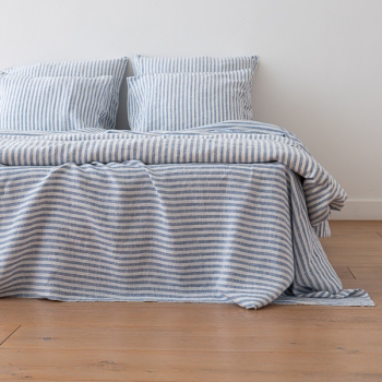 Blue Ticking Stripe linen bedding draped over the side of a bed